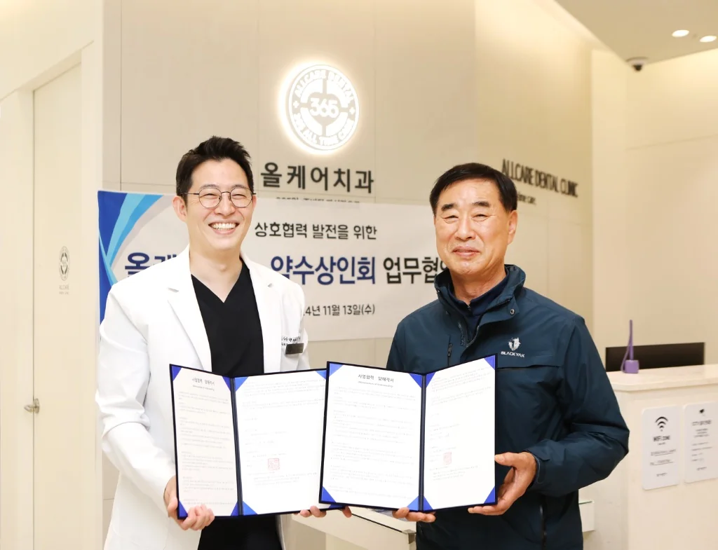 올케어치과 - 약수상인회 업무협약식 — 권민수 대표원장이 상인회 대표와 상호협력 협약서에 서명하는 모습